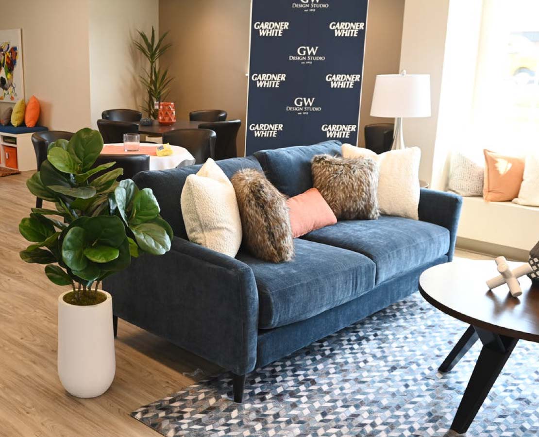 Blue couch with fuzzy pillows next to a house plant